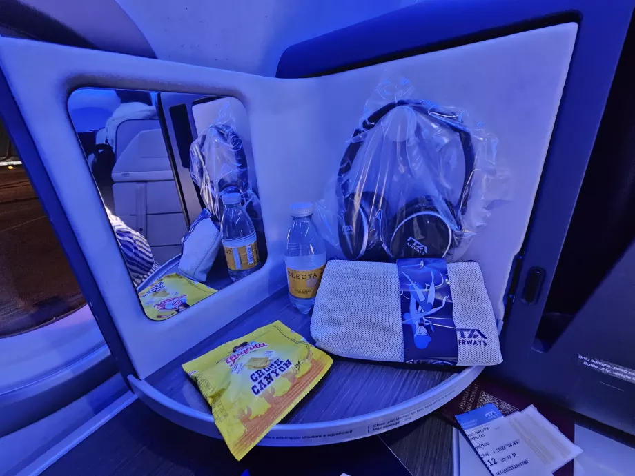 Panel pembuka dengan cermin, headphone, biskuit, dan air