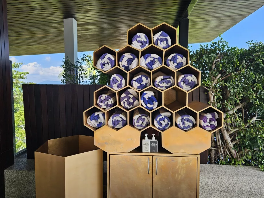 Handuk dan tabir surya di tepi kolam renang