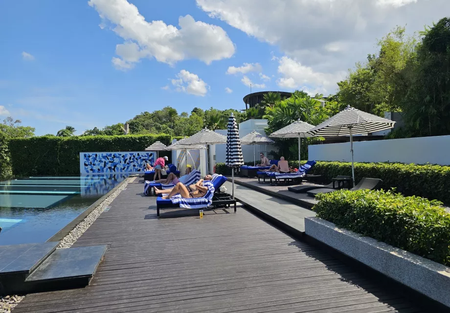 Kursi berjemur di tepi kolam renang komunal